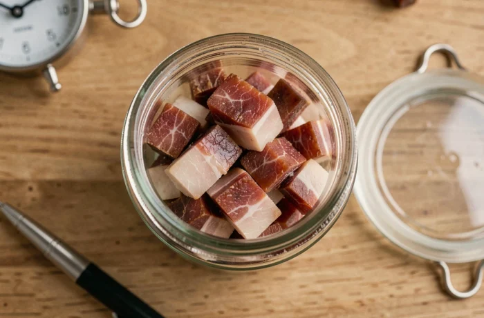 Bacon bits stored in an airtight glass container placed on a wooden countertop